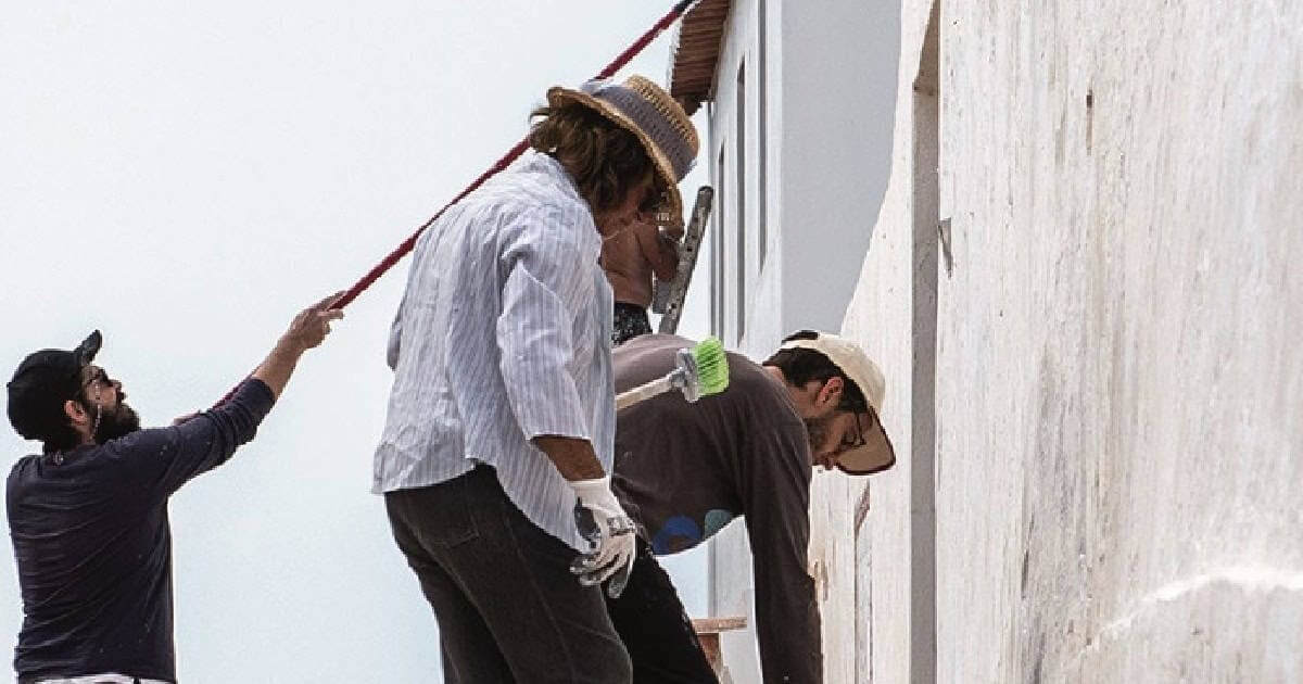 Pessoas pintando fachada branca de edifício. - Cacela Velha